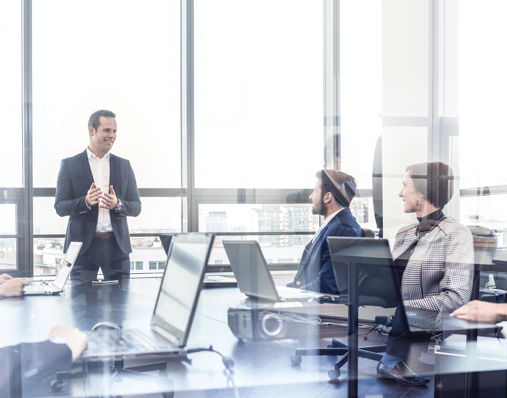 Successful team leader and business owner leading informal in-house business meeting. Businessman working on laptop in foreground. Business and entrepreneurship concept.
