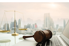 law legal technology concept. judge gavel on computer with scales of justice on desk of lawyer.