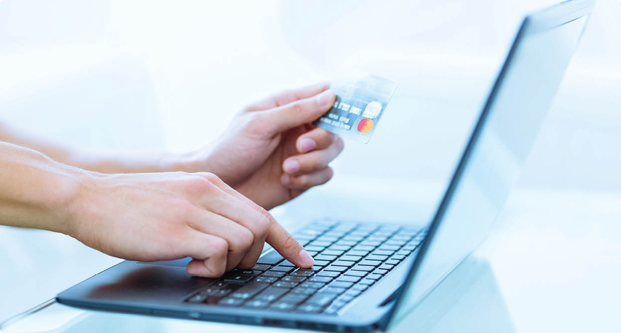 Close-up of hands shopping/paying online using laptop and credit card.