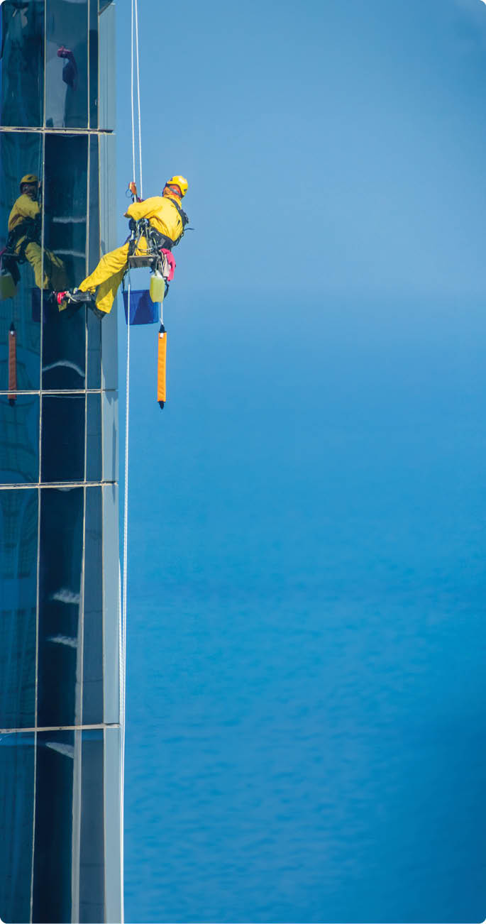 Worker Cleaning a Facade of One of the Buildings in Downtown Abu Dhabi. Abu Dhabi - UAE. 19 December 2018