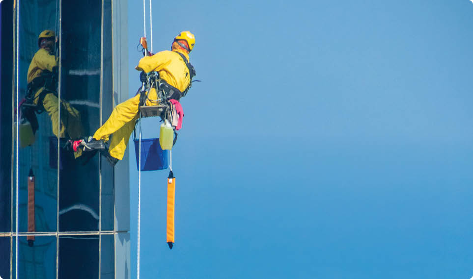 Worker Cleaning a Facade of One of the Buildings in Downtown Abu Dhabi. Abu Dhabi - UAE. 19 December 2018