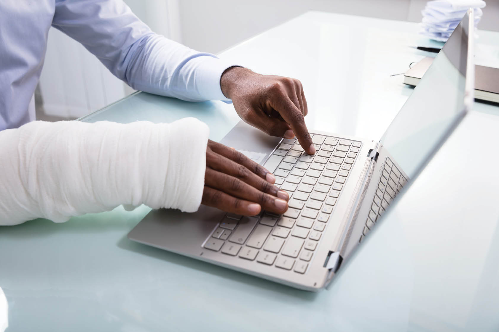 Close-up Of A Businessman With Bandage Hand Using Laptop At Workplace