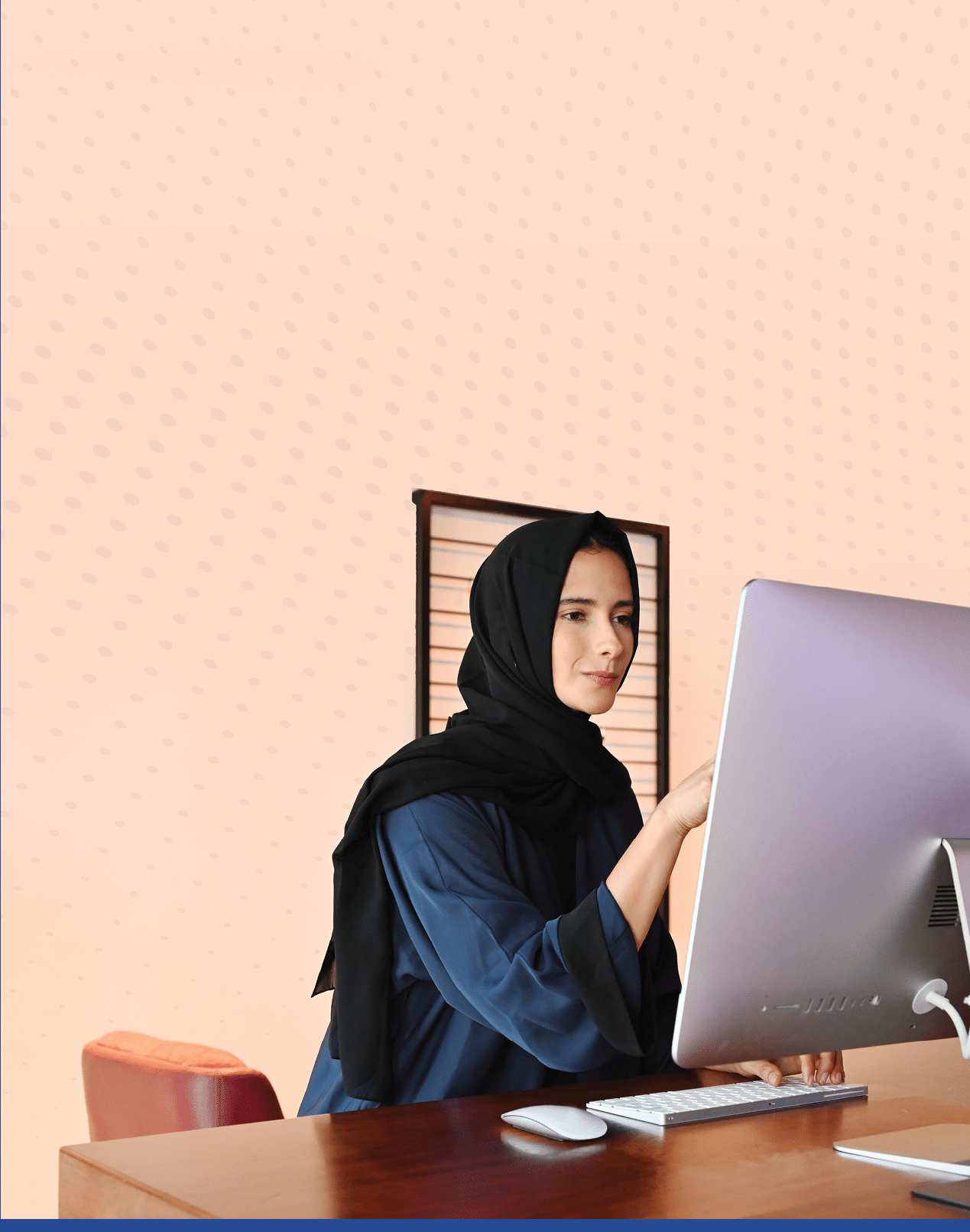 Beautiful Middle Eastern woman using desktop computer screen wearing traditional Hijab and Abaya head scarf.