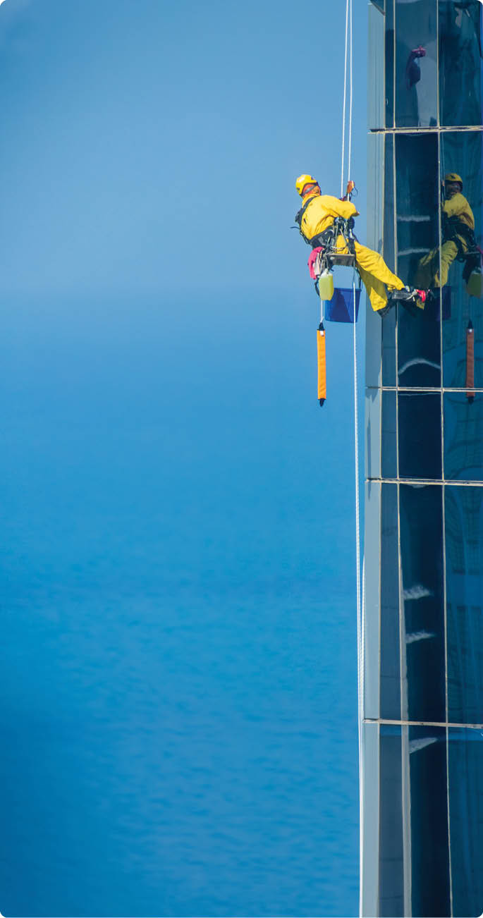 Worker Cleaning a Facade of One of the Buildings in Downtown Abu Dhabi. Abu Dhabi - UAE. 19 December 2018