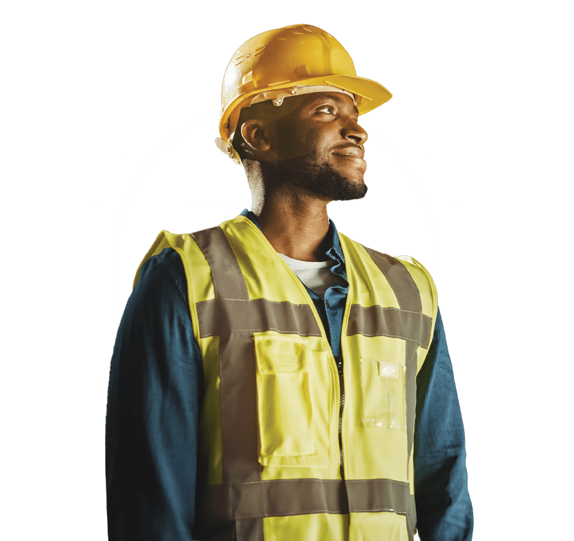 Handsome Professional Worker Wearing Safety Vest and Hard Hat Charmingly Smiling and Looks Into the Distance. In the Background Big Warehouse with Shelves full of Delivery Goods. Medium Portrait