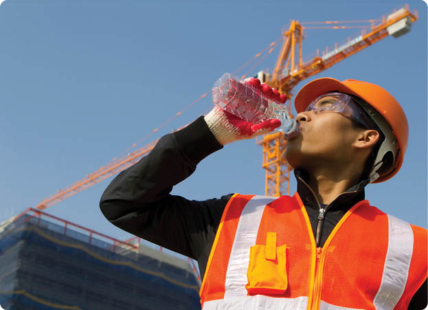 worker man as he drinks from a plastic water bottle on construction site