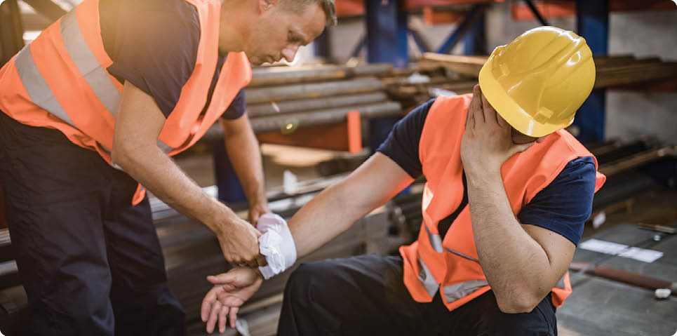 Manual worker feeling pain after having an injury at work while his colleague is helping him.